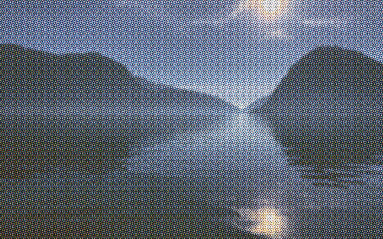 Alpine lake photo as a four-color CMYK process print with visible rosette dots.