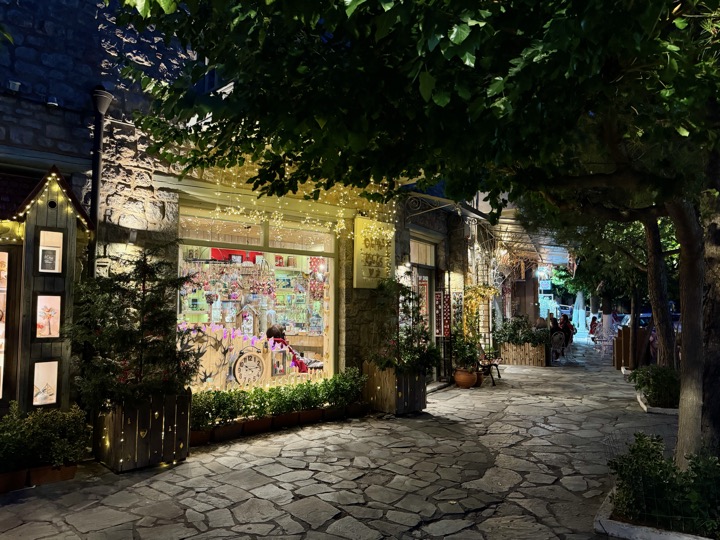 Cobbled old-town lane with warm shop lights in the evening.