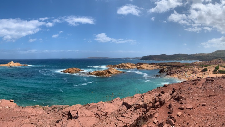 Turquoise cove framed by red rocks on a wild coast.